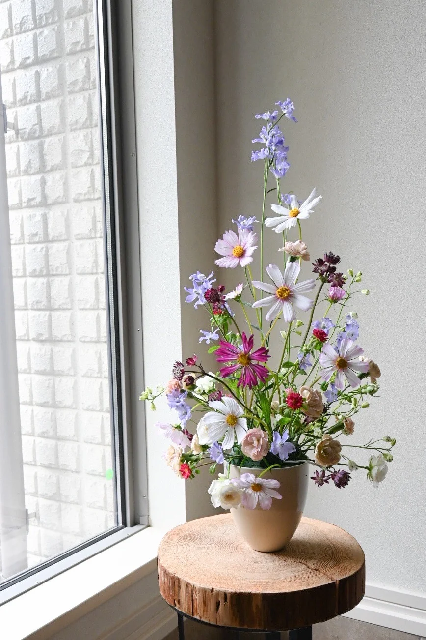 自然光の入る窓辺に飾られた、ピンクや紫の季節の花